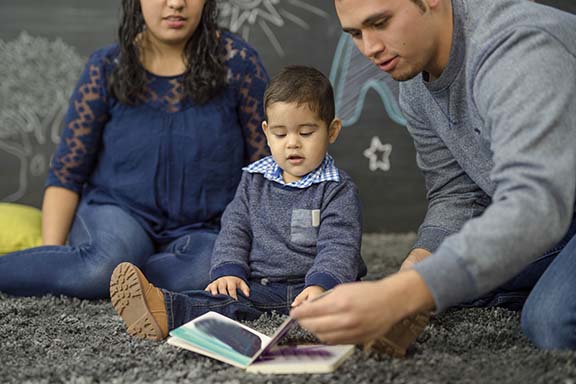 Ethnic parents reading with their toddler in a playroom